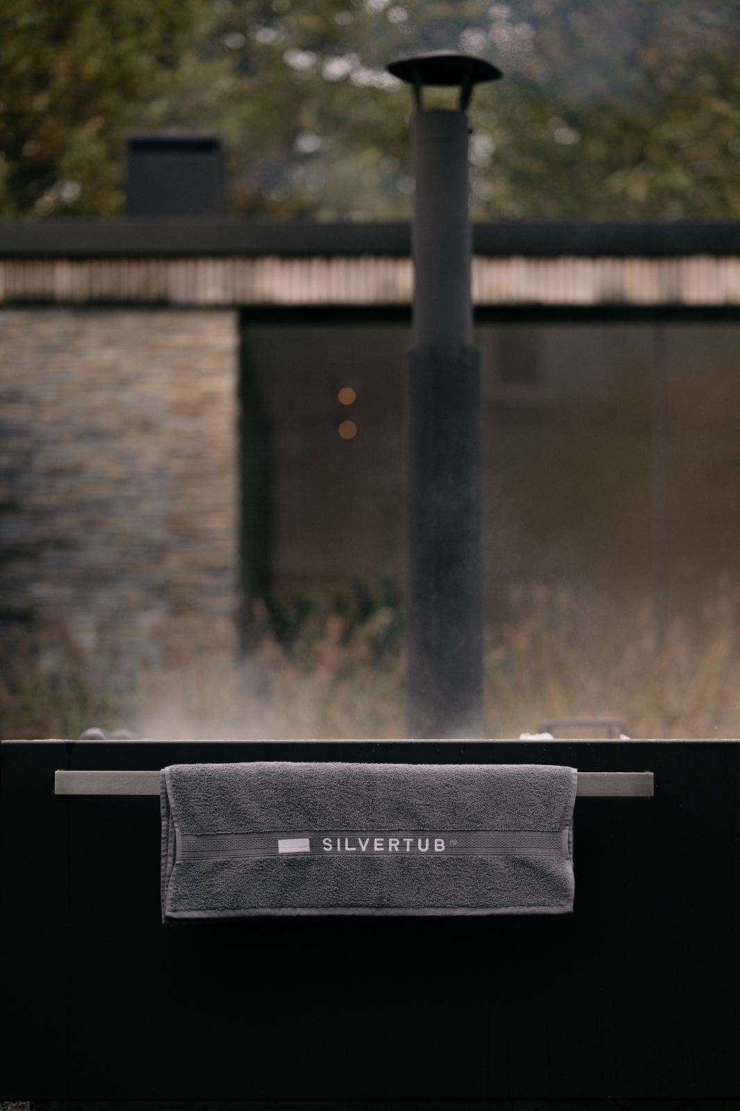 Stoom boven een Silvertub in de avond, met de houtkachelschouw erachter